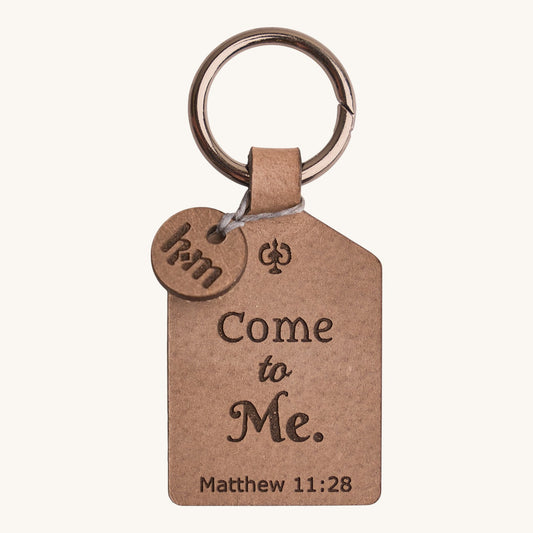 Holy Matters vegetable-tanned leather keychain engraved with Come to Me Matthew 11:28 scripture and a small HM charm.