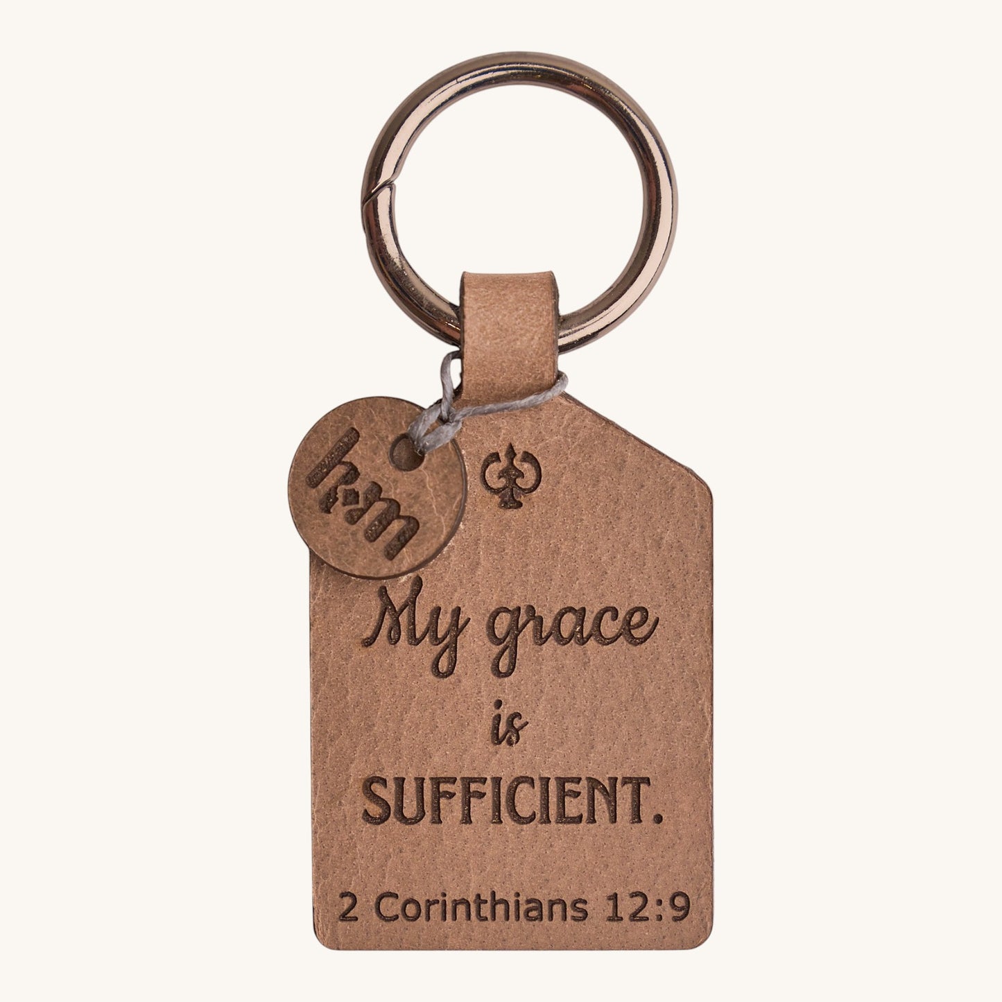 Holy Matters vegetable-tanned leather keychain engraved with 2 Corinthians 12:9 scripture and a small logo charm.