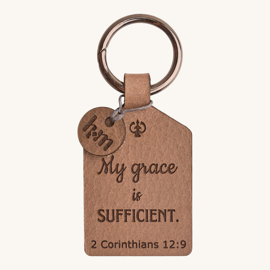 Holy Matters vegetable-tanned leather keychain engraved with 2 Corinthians 12:9 scripture and a small logo charm.